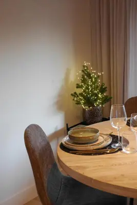 a wooden table with plates and wine glasses and a christmas tree at Parus major in Londerzeel