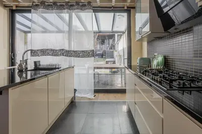 a kitchen with white cabinets and a large window at Kweni House in Brussels