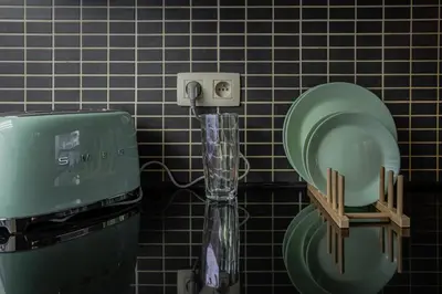 a soap dispenser next to a green toilet in a bathroom at Kweni House in Brussels