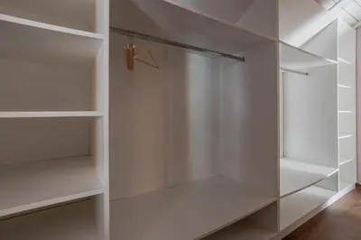 a white walk in closet with white shelves at Kweni House in Brussels