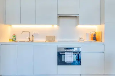 a white kitchen with white cabinets and a sink at Cozy & Bright Stay in Ghent - Parking Included in Ghent