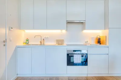 a kitchen with white cabinets and a sink at Cozy & Bright Stay in Ghent - Parking Included in Ghent