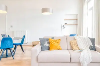 a living room with a white couch with colorful pillows at Cozy & Bright Stay in Ghent - Parking Included in Ghent