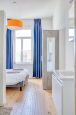 a bedroom with a bed and blue curtains at Cozy & Bright Stay in Ghent - Parking Included in Ghent