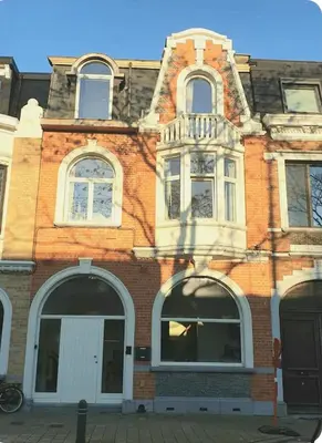 a brick building with white windows on a street at Mi casa es su casa in Ghent