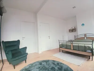 a bedroom with a bed and a green chair at Mi casa es su casa in Ghent