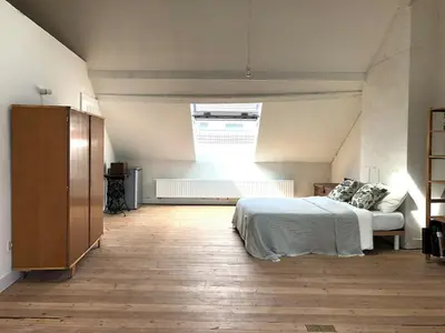 a bedroom with a bed and a large window at Penthouse studio in a family house in Brussels