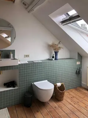 a bathroom with a toilet and green tile at Penthouse studio in a family house in Brussels