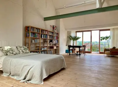 a bedroom with a bed and a table in a room at Penthouse studio in a family house in Brussels