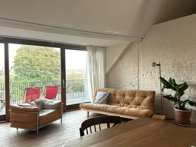 a living room with a couch and a table at Penthouse studio in a family house in Brussels