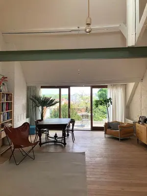 a large living room with a table and chairs at Penthouse studio in a family house in Brussels