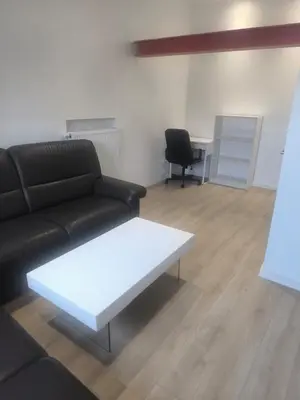 a living room with a black couch and a white coffee table at Nice apartment close to Zaventem airport in Kampenhout