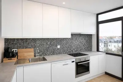 a kitchen with white cabinets and a sink and a window at Avenue Louise skyline view in Brussels
