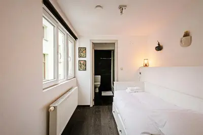 a white bedroom with a bed and a window at Central Ghent Apartment for 3 Guests in Ghent