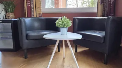 two black leather chairs and a table with a vase of flowers at Green Hill Guest Room Overijse in Overijse