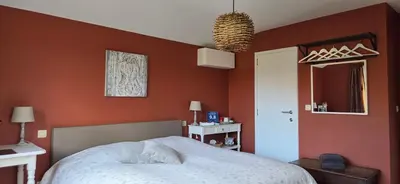 a bedroom with an orange wall with a bed and a window at Green Hill Guest Room Overijse in Overijse