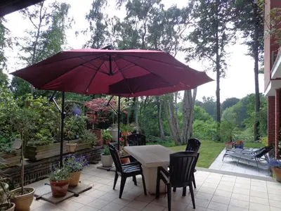 a table and chairs with a red umbrella on a patio at Green Hill Guest Room Overijse in Overijse