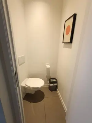 a bathroom with a white toilet in a room at Studio charmoso in Brussels