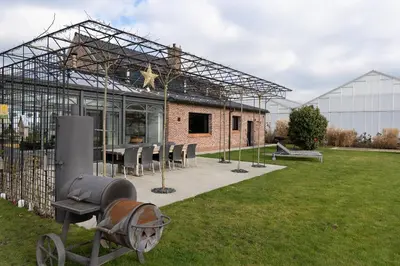 a greenhouse with a table and chairs in a yard at Vakantiehoeve Breathe Nature in Lochristi