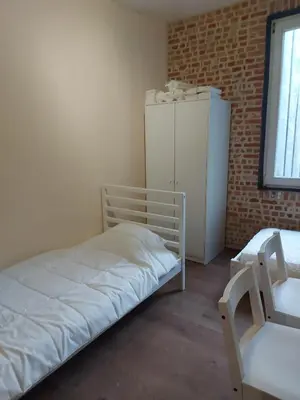a small room with a bed and a refrigerator at Deurne in Antwerp
