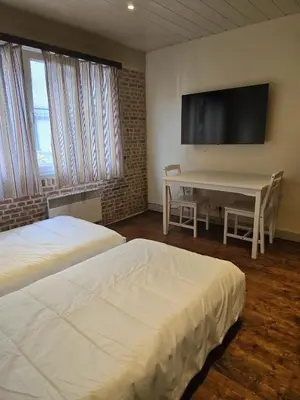 a room with two beds and a table and a tv at Schijnpoort in Antwerp