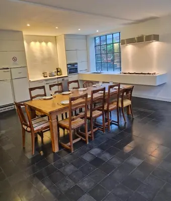 a kitchen with a wooden table and wooden chairs at Furnished house BXL- for team of workers in Beersel