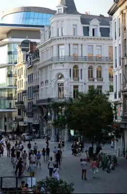 a group of people walking in a street in front of a building at Grand Place Bourse Prestige in Brussels