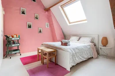 a bedroom with a bed with a pink wall at Cozy loft in private house at the center of Ghent in Ghent