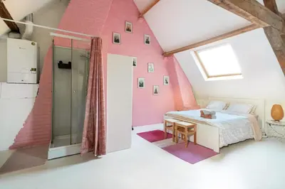a bedroom with pink walls and a bed and a table at Cozy loft in private house at the center of Ghent in Ghent