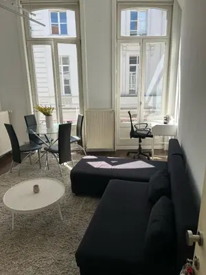 a living room with a couch and a table and windows at Cosy studio in prime location in Ghent