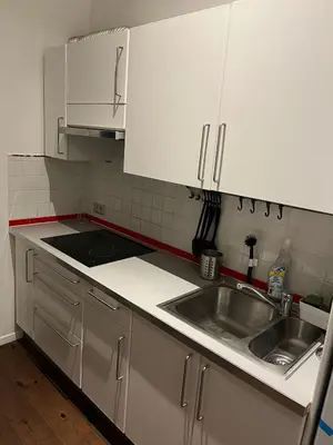 a kitchen with white cabinets and a sink at Cosy studio in prime location in Ghent