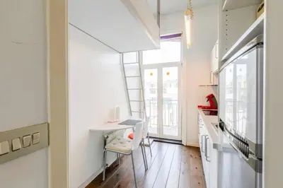 a kitchen with white cabinets and a table and a window at Cosy studio in prime location in Ghent