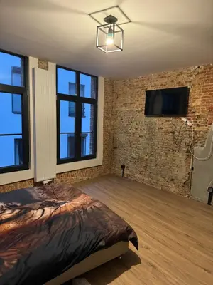 a bedroom with a bed and a tv on a brick wall at Мини студия in Antwerp