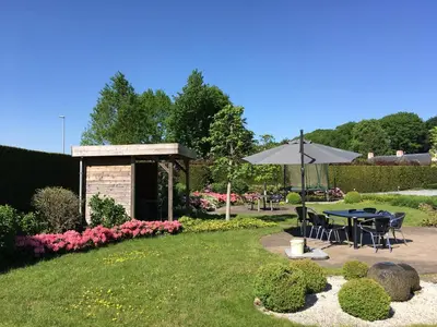 a garden with a table and an umbrella at Hotel Cleo in Kasterlee