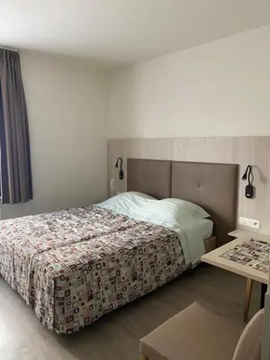 a bedroom with a bed and a table at Hotel Cleo in Kasterlee