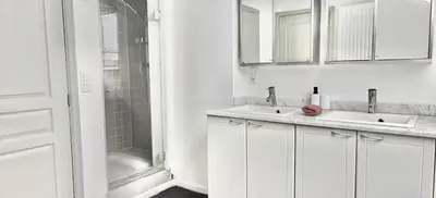 a white bathroom with two sinks and a shower at Spacious terrace apartment in the heart of Brussels in Brussels