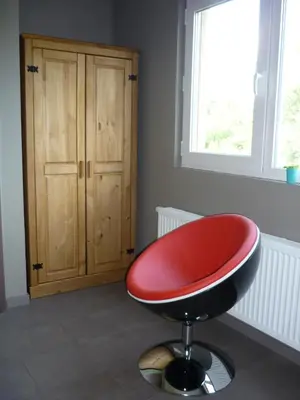a red chair sitting in a room with a cabinet at B&B Wiezebed in Wieze