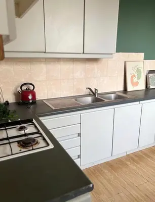 a kitchen with white cabinets and a stove and sink at Purple Sofa in Antwerp