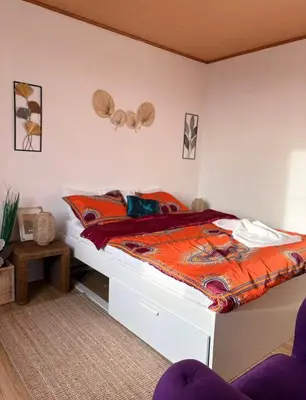 a bedroom with a bed with an orange comforter at Purple Sofa in Antwerp