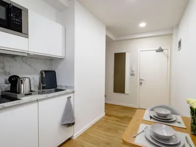 a kitchen with white cabinets and a table at Charmant Studio - Centre-ville - 2min de Métro - 401 in Brussels