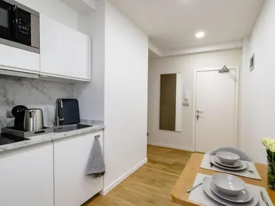 a kitchen with white cabinets and a wooden table at Cozy Studio - Downtown - 2 min from Metro - 201 in Brussels