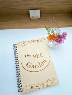 a notebook with the bee garden written on it on a desk with flowers at The BEE Garden in Lede