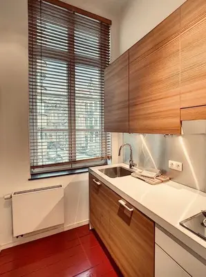 a kitchen with wooden cabinets and a sink and a window at Loft a stone's throw from Place Brugmann in Brussels