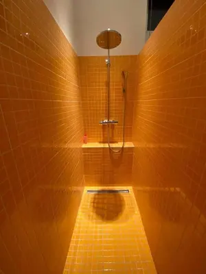 a yellow tiled bathroom with a shower and a toilet at Loft a stone's throw from Place Brugmann in Brussels