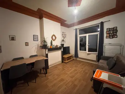 a living room with a table and a couch and a television at Appartement in Brussels