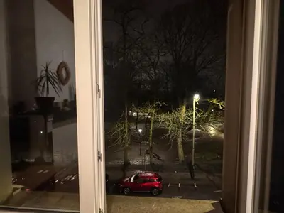 a red car parked outside a window at night at Appartement in Brussels