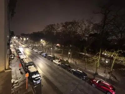 a view of a city street at night with cars parked at Appartement in Brussels