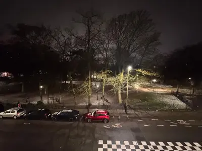 a parking lot at night with cars parked at Appartement in Brussels