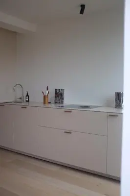 a kitchen with white cabinets and a sink at Design appartement met zonnig terras bij Gravensteen in Ghent