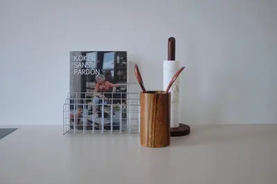 a vase with pens in it next to a book at Design appartement met zonnig terras bij Gravensteen in Ghent